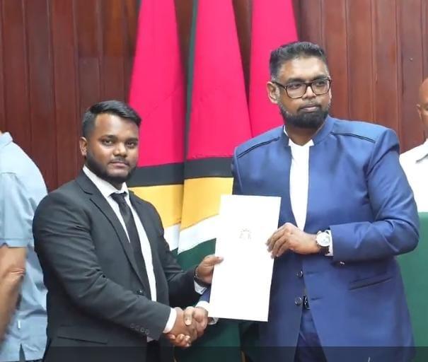 President Irfaan Ali presents a certificate to one of the newly appointed land surveyors.