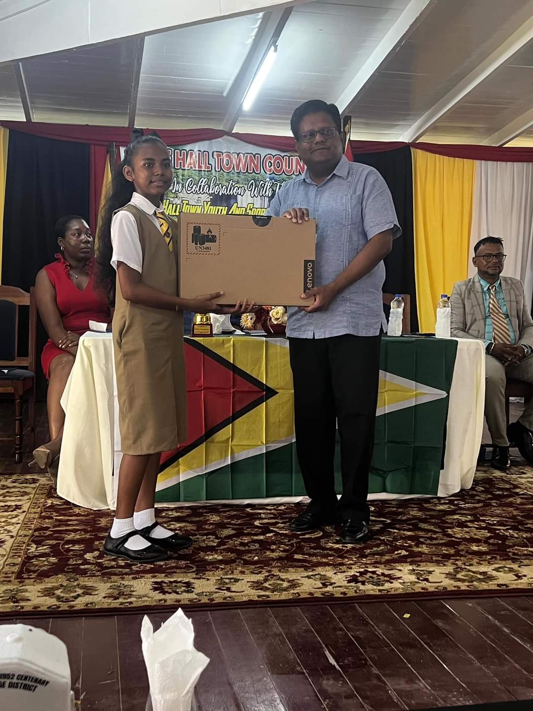 Top grade six student Calicia Narain receives her laptop computer from Minister Singh.